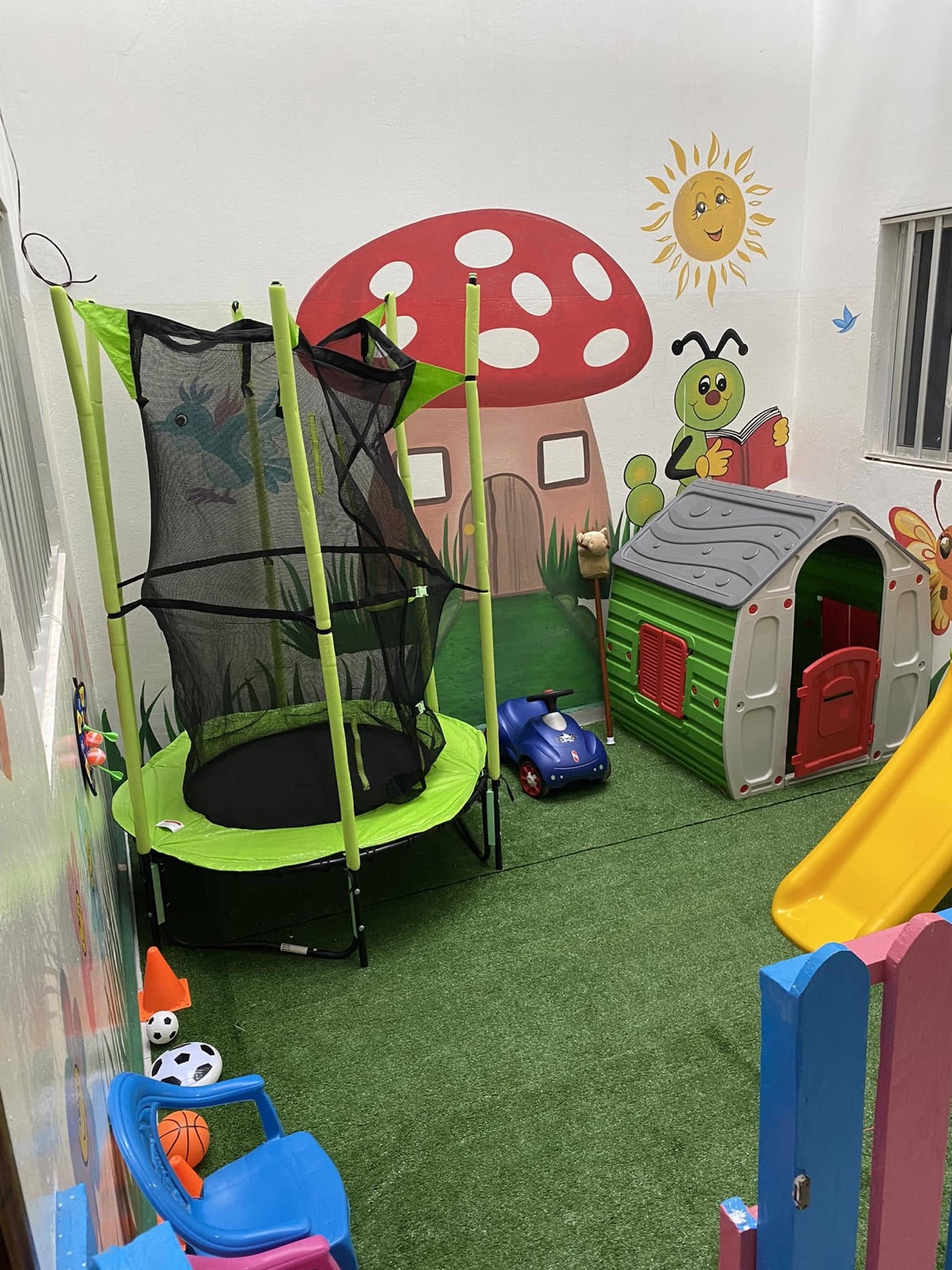 L’espace de jeux de l’école avec trampoline, toboggan et maison de jeu